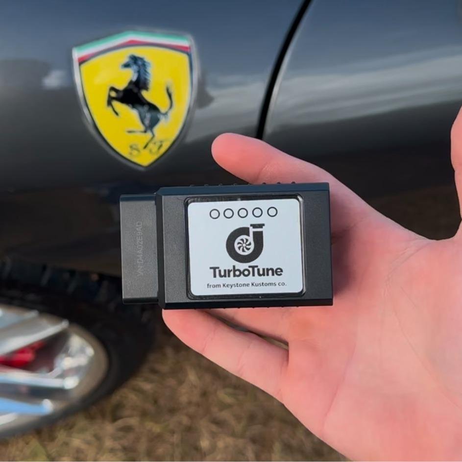TurboTune device held in front of a Ferrari